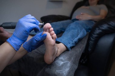 Güzellik salonunda hırdavat pedikür yapan hamile bir kadın.
