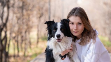 Sonbahar parkında sınır köpeğini kucaklayan beyaz bir kadın. Köpekli bir kızın portresi.