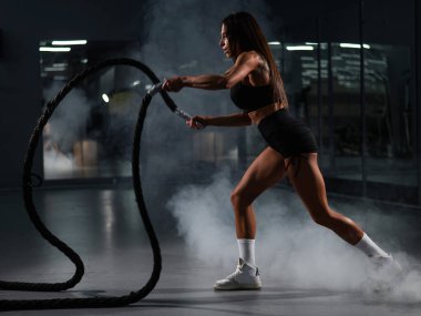 Beyaz kadın halatlarla egzersiz yapıyor. Spor salonunda tur eğitimi.