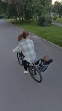 Beyaz kadın oğluyla bisiklete biniyor. Dikey video