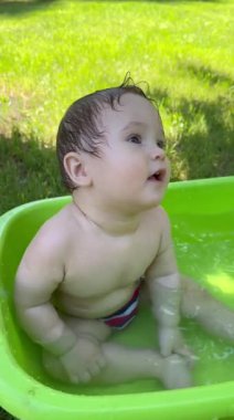 Yazın dışarıdaki havuzda şirin bebek banyosu yapıyor. Dikey video