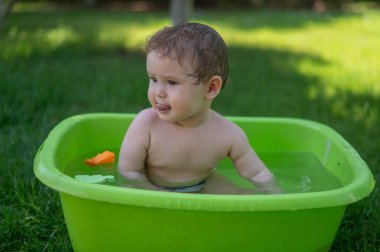 Tatlı erkek bebek yazın havuzda yıkanır.