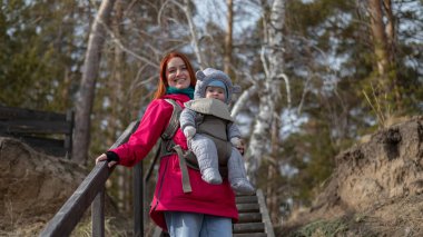Kafkasyalı kızıl saçlı kadın kışın doğada oğluyla birlikte sırt çantasıyla dolaşıyor.