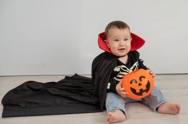 Beyaz arka planda şeker sepeti tutan Dracula Cadılar Bayramı kostümlü beyaz tatlı çocuk.