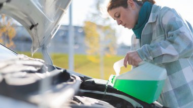 Caucasian woman filling car reservoir with windshield washer fluid from bottle clipart