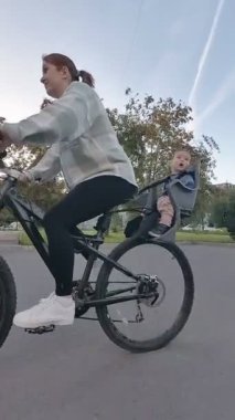 Beyaz kadın oğluyla bisiklete biniyor. Dikey video