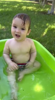 Yazın dışarıdaki havuzda şirin bebek banyosu yapıyor. Dikey video