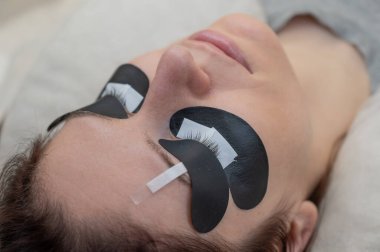 Kirpik uzatma prosedüründen geçen bir kadın ultraviyole lamba kullanıyor.