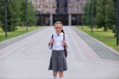 Beyaz kız öğrenci portresi. Üniformalı ve sırt çantalı.