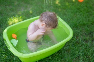 Tatlı erkek bebek yazın havuzda yıkanır.