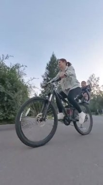 Beyaz kadın oğluyla bisiklete biniyor. Dikey video
