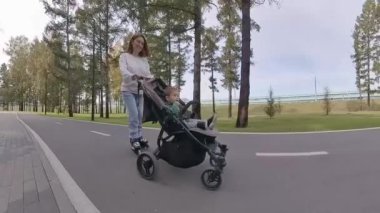 Beyaz kadın bebek arabasıyla küçük oğluyla paten kayıyor.