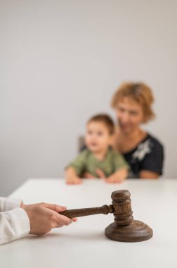 Hakim, elinde çocuk tutan yaşlı bir kadının arka planına vuruyor.