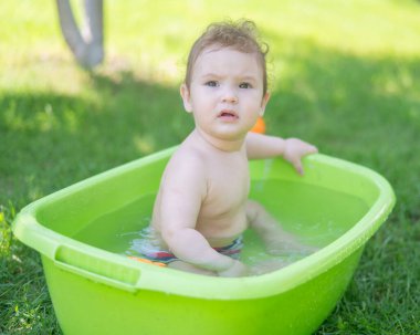 Tatlı erkek bebek yazın havuzda yıkanır.