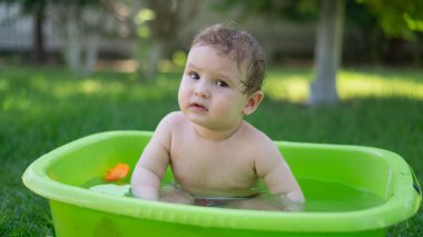 Tatlı erkek bebek yazın havuzda yıkanır.