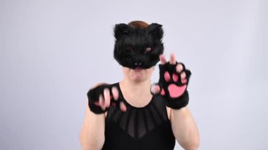 Beyaz kadın kedi maskesini çıkarıyor. Kuadrober