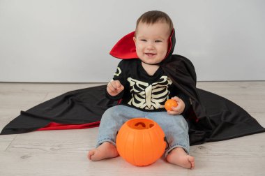 Beyaz arka planda şeker sepeti tutan Dracula Cadılar Bayramı kostümlü beyaz tatlı çocuk.