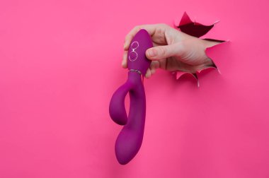 Pembe kağıttan yapılmış ahududulu seks oyuncağıyla takılan bir kadın eli.