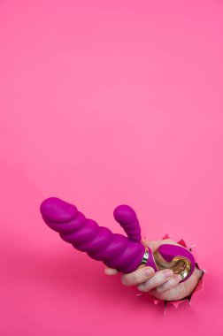 Pembe kağıttan yapılmış pembe seks oyuncağıyla dışarı çıkmış bir kadın eli. Uzayı kopyala Dikey fotoğraf