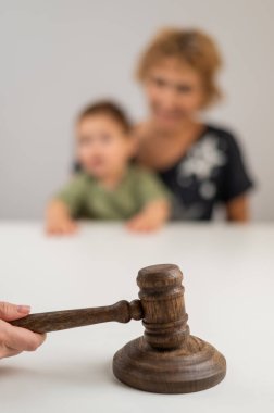 Hakim, elinde çocuk tutan yaşlı bir kadının arka planına vuruyor.