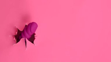 Pembe kağıttan yapılmış pembe seks oyuncağıyla dışarı çıkmış bir kadın eli. Boşluğu kopyala