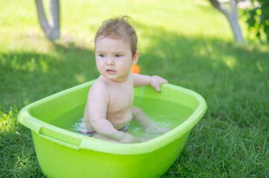 Tatlı erkek bebek yazın havuzda yıkanır.