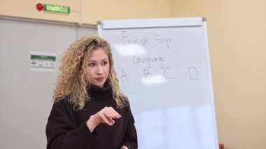 Beyaz kadın üniversitede işaret dili öğretiyor.