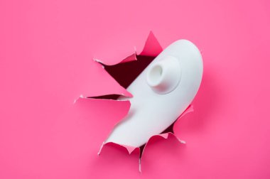 Beyaz vakumlu klitoral vibratör pembe kağıt arkaplanından sarkıyor. Seks oyuncağı