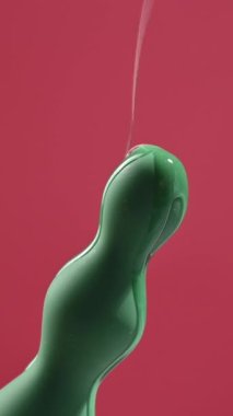Pembe arka planda yeşil anal boncuklara yağ dökülüyor.