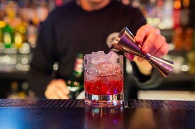 Barmen kırmızı kokteyl koyuyor.