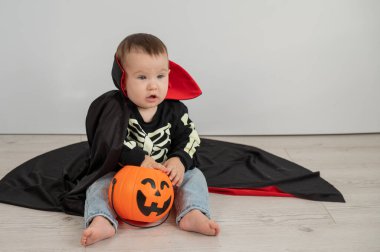 Beyaz arka planda şeker sepeti tutan Dracula Cadılar Bayramı kostümlü beyaz tatlı çocuk.