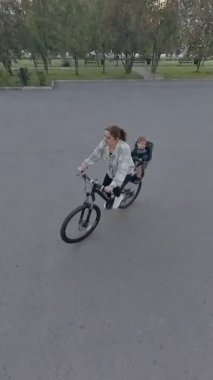 Beyaz kadın oğluyla bisiklete biniyor. Dikey video