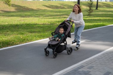 Beyaz kadın bebek arabasıyla küçük oğluyla paten kayıyor.