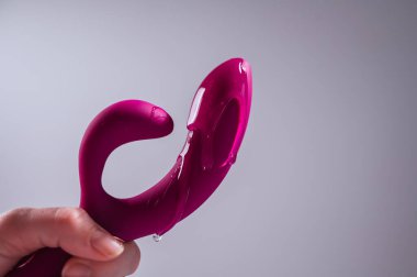 Lube pouring on pink dildo on white background