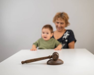 Yaşlı bir kadın jürinin arkasında bir çocuk tutuyor.