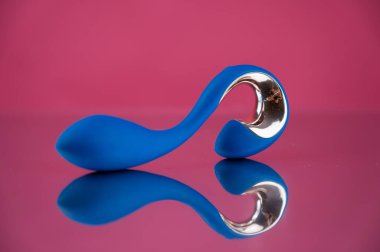 Blue sex toy on mirrored pink surface clipart