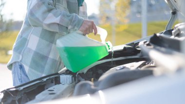 Kadın ellerinin araba deposunu şişeden çıkan cam yıkama sıvısıyla doldurduğu yeri kapatın.