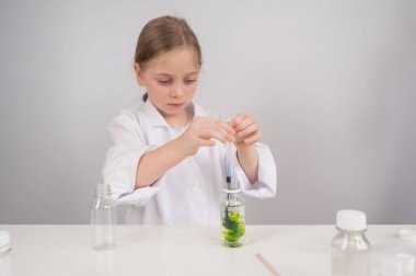 Beyaz arka planda kimyasal deneyler yapan beyaz bir kız.