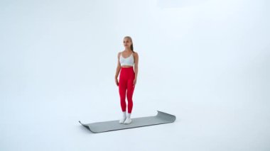 Beyaz arka plan üzerinde bölme egzersizi yapan genç kadın