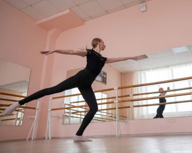 Kafkasyalı sarışın kadın sınıfta bale çalışıyor. Balerin barda prova yapıyor.