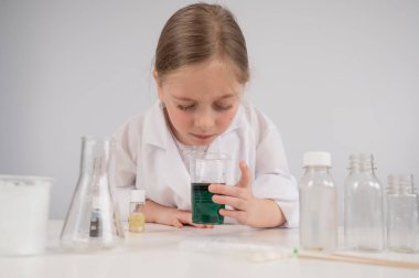 Beyaz arka planda kimyasal deneyler yapan beyaz bir kız.