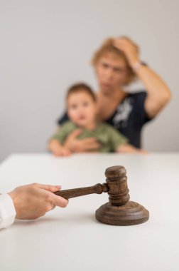 Hakim, elinde çocuk tutan yaşlı bir kadının arka planına vuruyor.