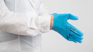Doktor beyaz bir arka plana lateks eldiven takar.