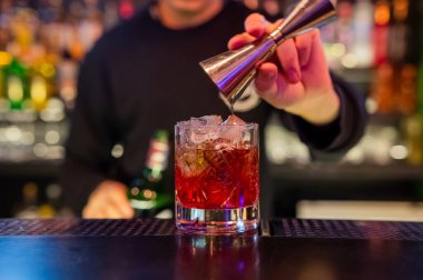 Barmen kırmızı kokteyl koyuyor.