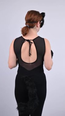 Kedi kostümü giymiş beyaz kadın dönüp miyavlıyor. Kuadrober