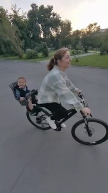 Beyaz kadın oğluyla bisiklete biniyor. Dikey video