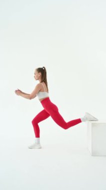 Beyaz arka planda kutuyla hareketler yapan genç bir kadın.