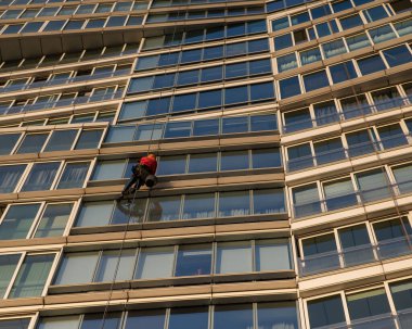 Bir adam bir gökdelenin camlarını siler. Endüstriyel yükseklik