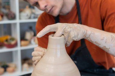 Çömlekçi elleriyle çömlekçi çarkında seramik vazo yaparken.