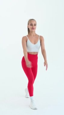 Beyaz siklonama arka planına atlama yapan genç bir kadın. Dikey video